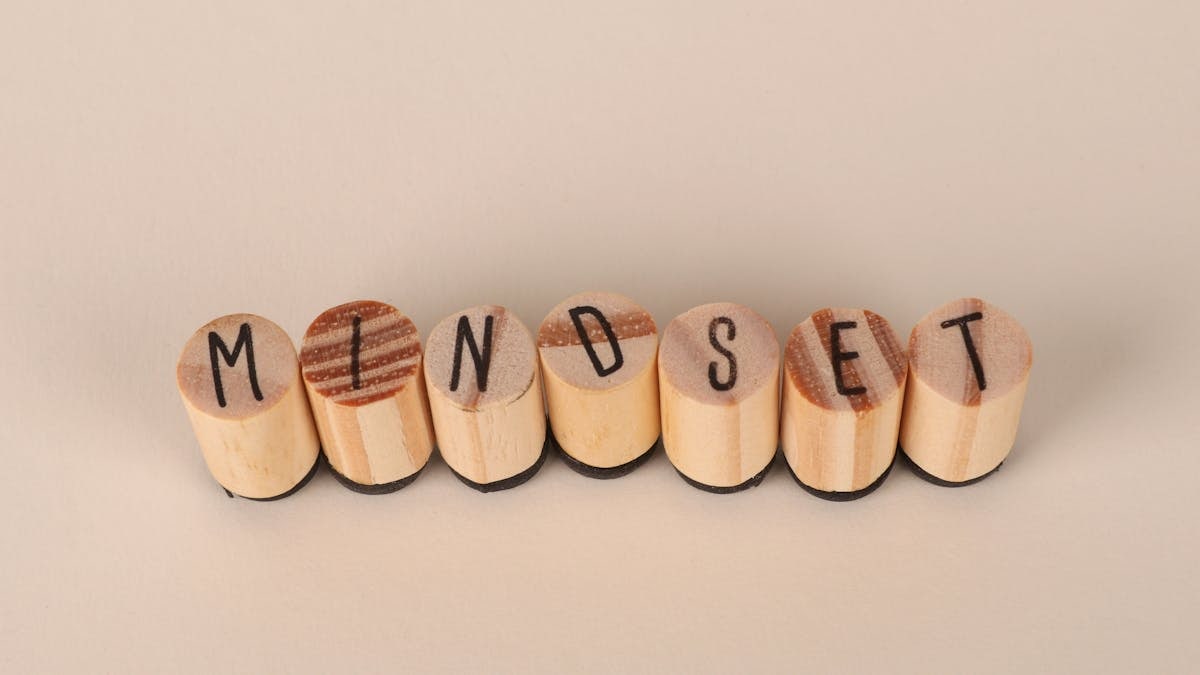 Wooden letter stamps spelling 'Mindset' on a simple beige background, conveying focus and positive thinking.